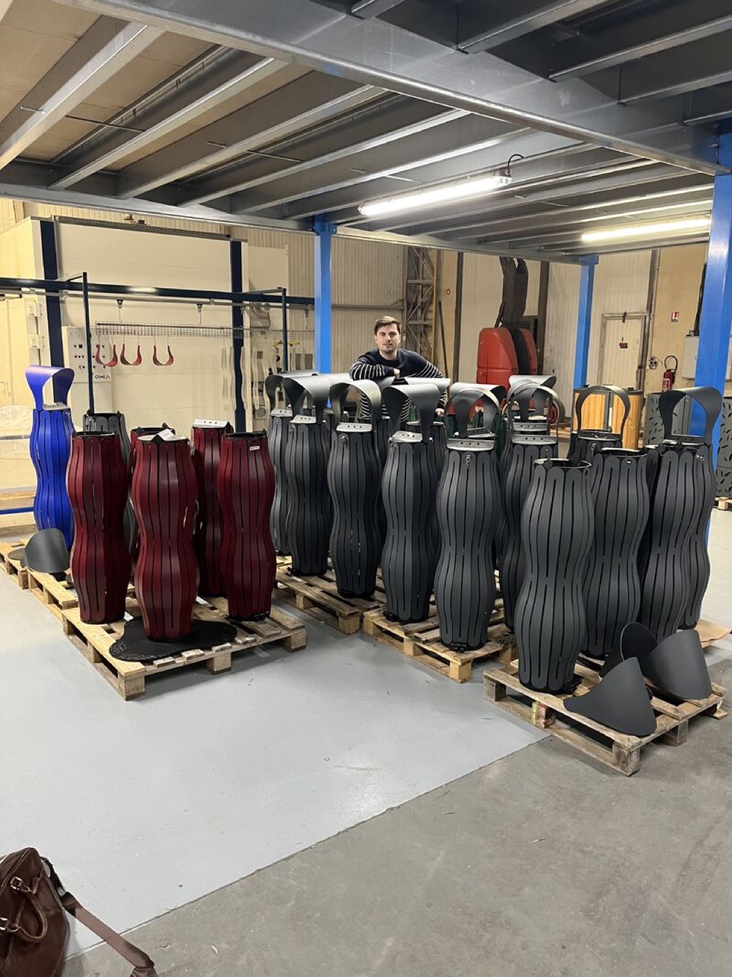 Plan large de l&rsquo;atelier&nbsp;: des palettes de cendriers bleu, rouge vigne et anthracite, un compagnon au milieu