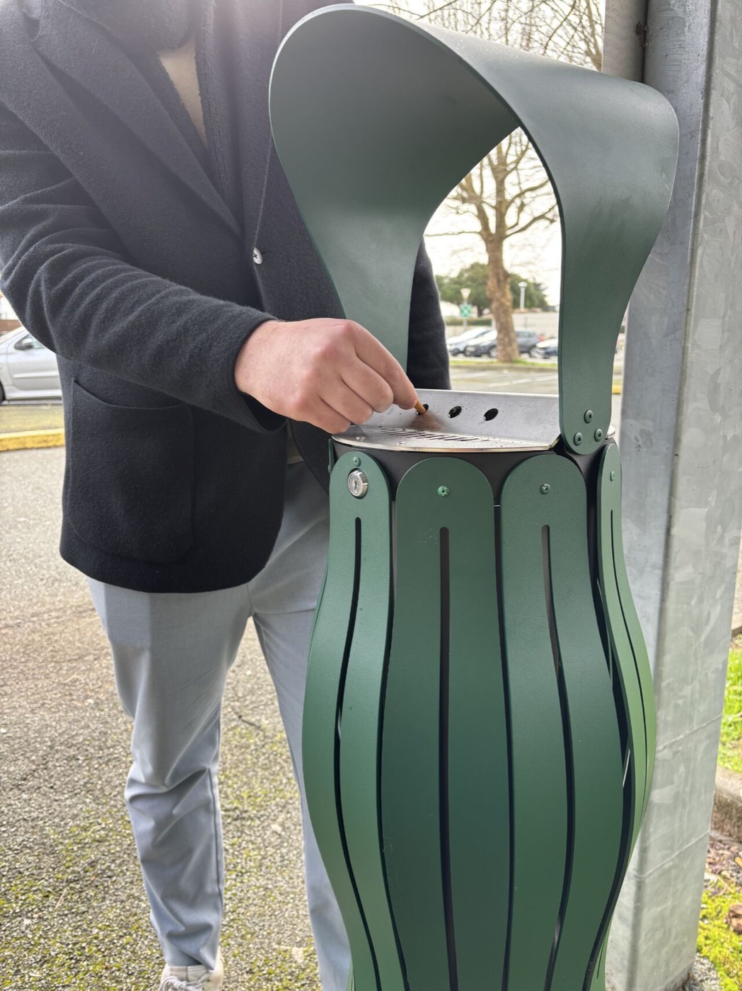 Une main &eacute;crase une cigarette sur le plateau inox perfor&eacute;, sous la coiffe