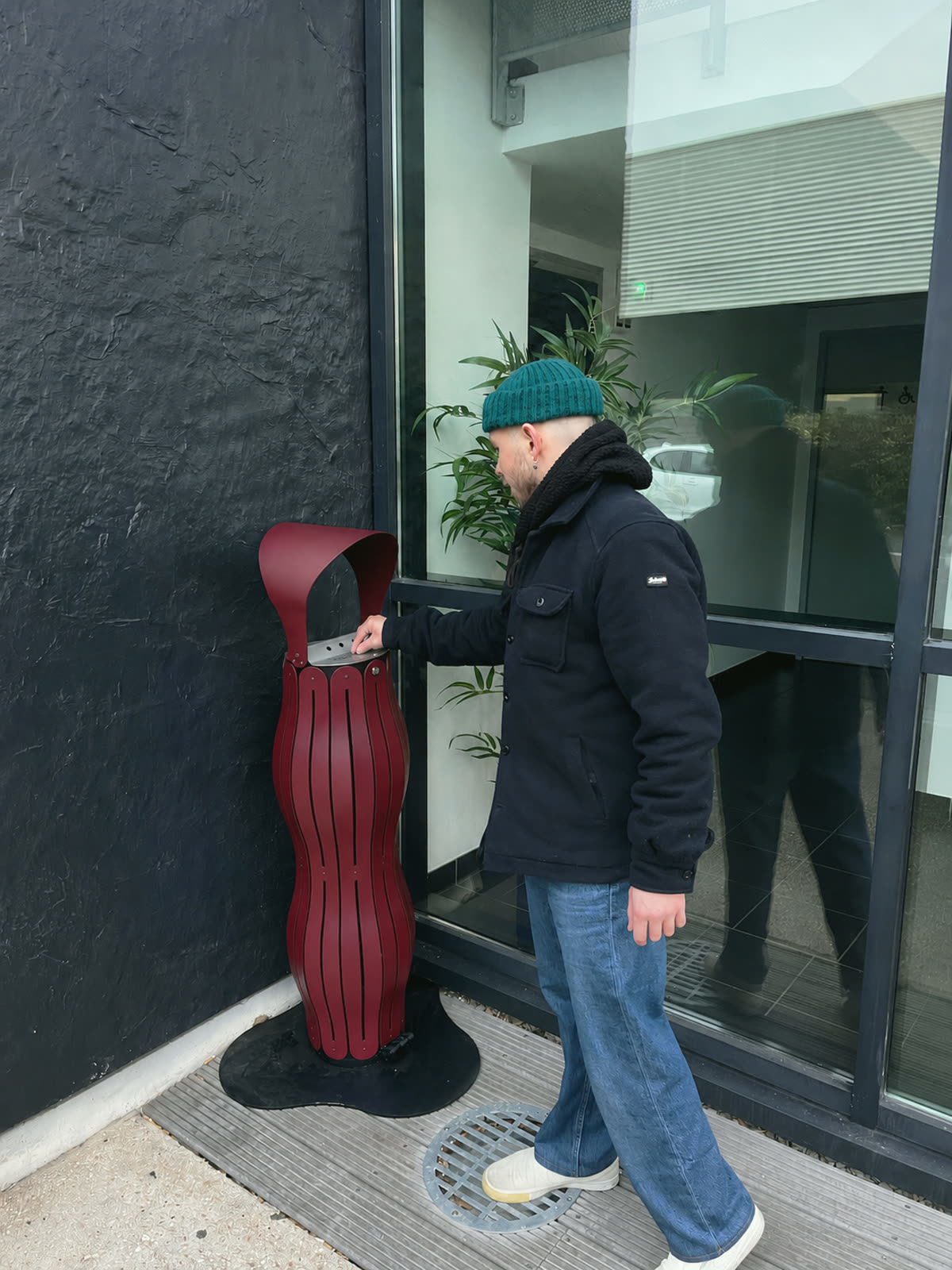 Un fumeur d&eacute;pose son m&eacute;got dans le cendrier, &agrave; l&rsquo;entr&eacute;e d&rsquo;un b&acirc;timent
