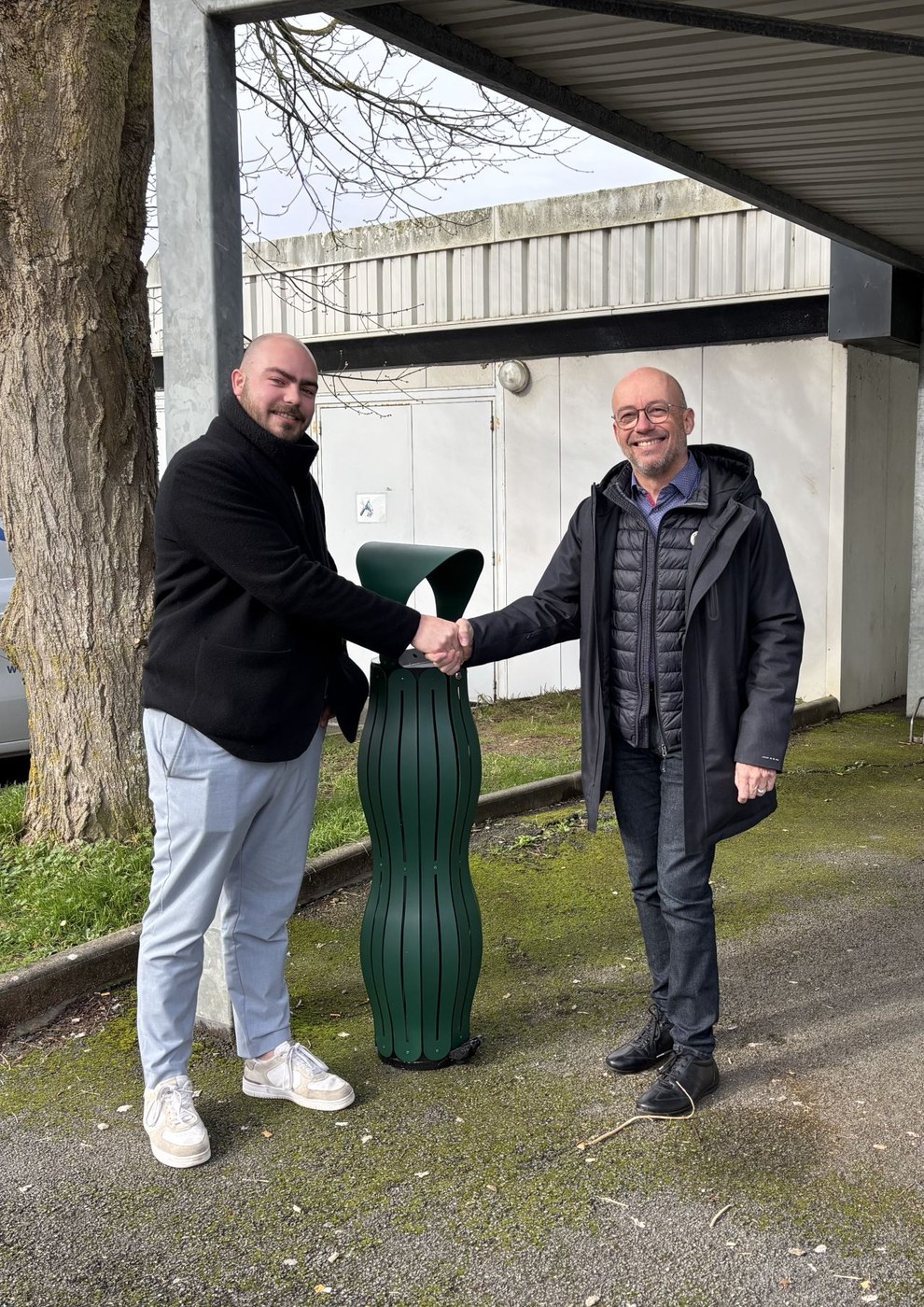 Notre commercial et un client se serrent la main devant un cendrier vert mousse fra&icirc;chement install&eacute;