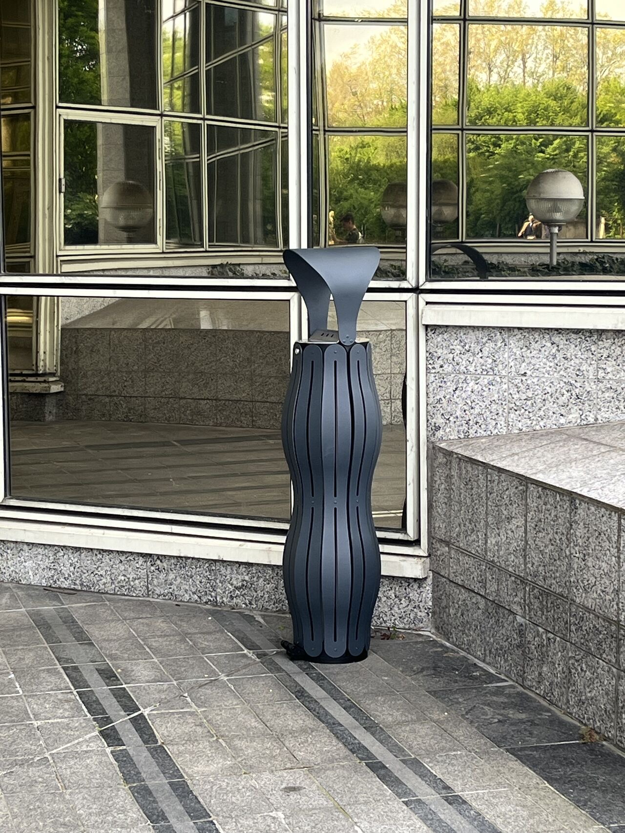 Cendrier gris anthracite sur le parvis d&rsquo;un immeuble tertiaire vitr&eacute;