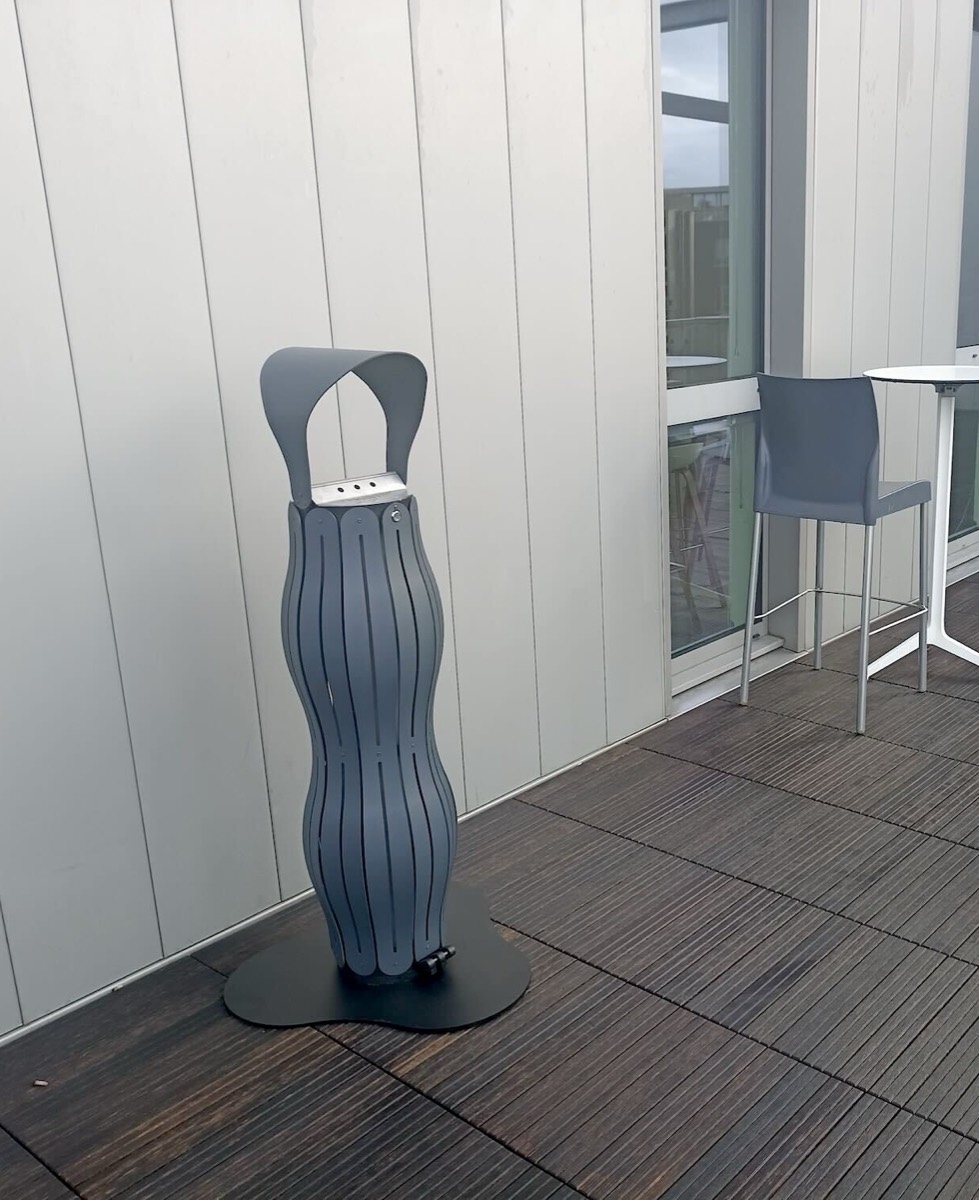 Cendrier vert en bout de terrasse, devant la fa&ccedil;ade vitr&eacute;e d&rsquo;un si&egrave;ge social