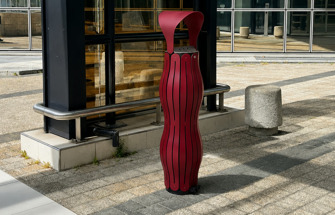 Cendrier rouge vigne sur un parvis ouvert au public, pr&egrave;s d&rsquo;un banc