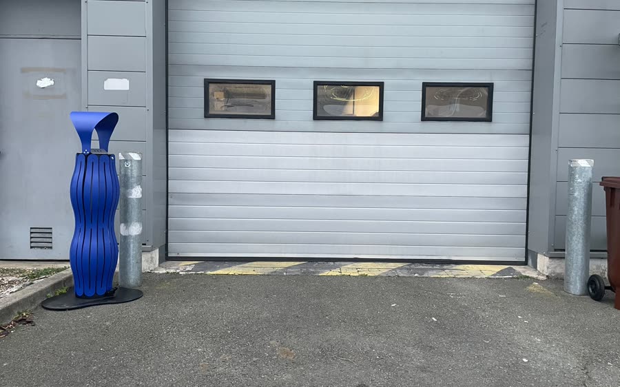Cendrier bleu pos&eacute; devant un b&acirc;timent industriel