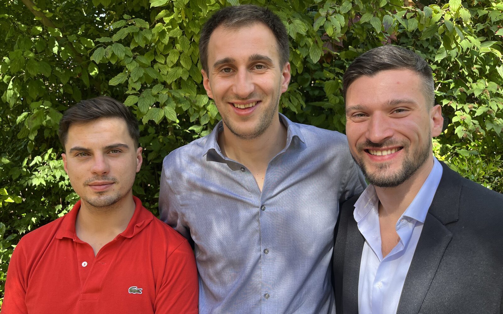 Les associés d'Easy to Change posant ensemble devant un mur de végétation
